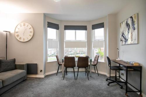 a living room with a table and chairs and a clock at Entire Luxurious 2 Bedroom Flat in Leicester