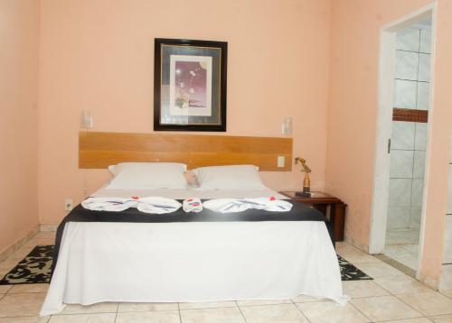 a bedroom with a white bed with a wooden headboard at Pousada Aconchego Shangrilla in Penedo