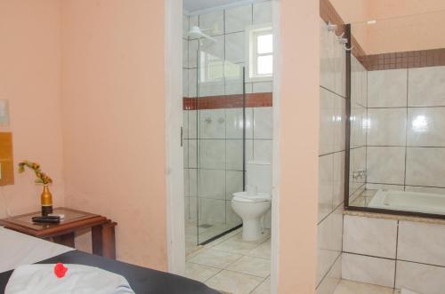 a bathroom with a shower and a toilet at Pousada Aconchego Shangrilla in Penedo