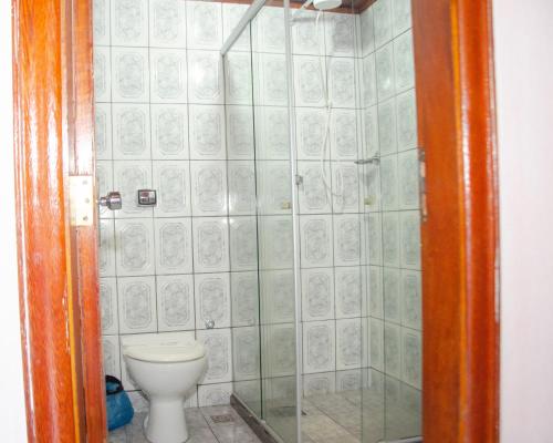 a bathroom with a toilet and a glass shower at Pousada Aconchego Shangrilla in Penedo