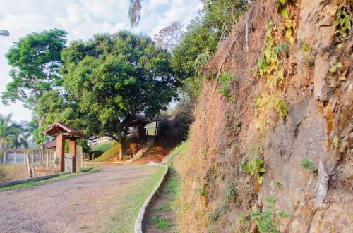 a dirt road next to a hill with trees at Pousada Aconchego Shangrilla in Penedo