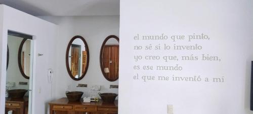 a bathroom with three mirrors and a writing on the wall at Del Carmen Concept Hotel Boutique by Chai in Guadalajara
