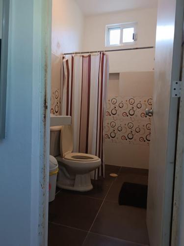 a bathroom with a toilet and a shower curtain at Casa Mara in Río Lagartos