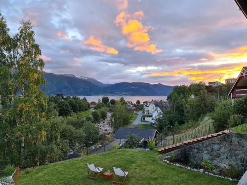 a view of a lake with two chairs on a lawn at Over the Fjord in Leikanger