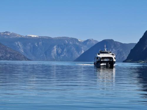 a boat on the water with mountains in the background at Over the Fjord in Leikanger