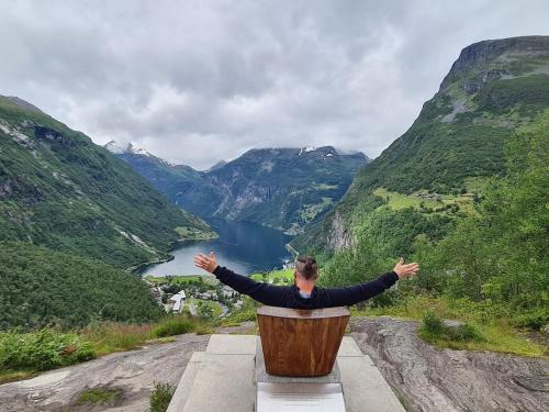 a woman sitting on a bench looking out over a valley at Over the Fjord in Leikanger