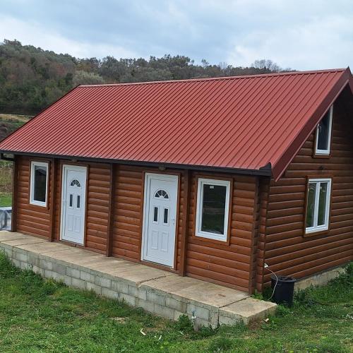 una baita di tronchi con porte bianche e tetto rosso di Cottage Kolomza a Ulcinj