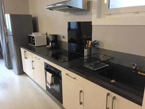 a kitchen with a black counter top and a refrigerator at Maison Cosy centre de Pouzauges in Pouzauges