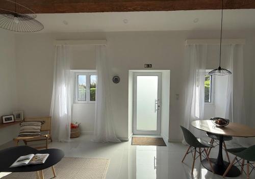 a white living room with a table and a door at Casa Amélia in Feteira Grande