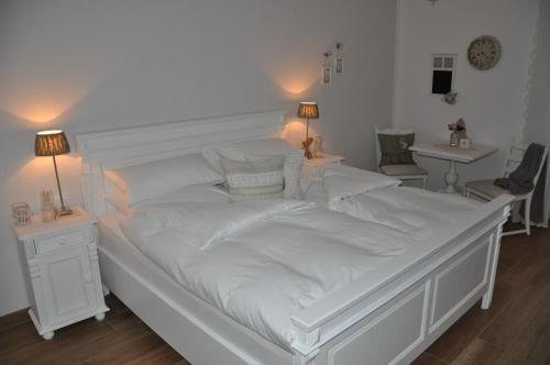 a large white bed with white sheets and pillows at White Cottage Garden in Cloppenburg