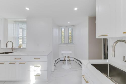 une cuisine blanche avec des comptoirs blancs et un tabouret dans l'établissement Mansion in the Mountains - Luxury, Peace & Family, à Suffern