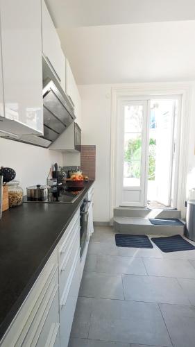 une cuisine avec des placards blancs et une grande fenêtre dans l'établissement Maison familiale hyper centre avec patio 6-7pers, à Villers-sur-Mer
