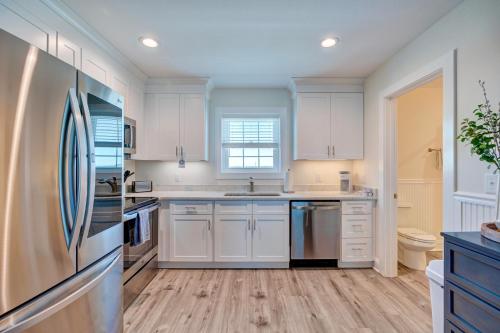 a kitchen with white cabinets and a refrigerator at Adjacent 2nd Floor, 2004 Queen & 2005 Queen in Surf City