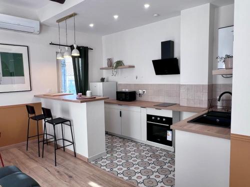 eine Küche mit weißen Schränken und einer Theke mit Barhockern in der Unterkunft Féria apartment city center in Béziers