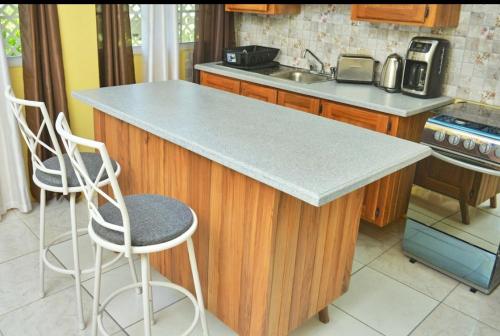 a kitchen with a counter and two stools in it at Essentials Suite in Bon Accord