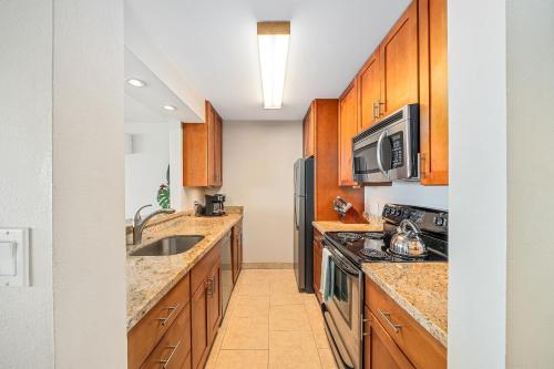 a kitchen with wooden cabinets and stainless steel appliances at Stunning ocean view 2 bedroom Steps from beach in Kihei
