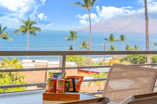 a table with a box of chips on a balcony with the ocean at Stunning ocean view 2 bedroom Steps from beach in Kihei