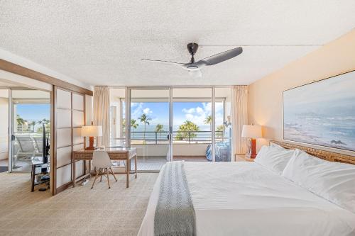a bedroom with a bed and a desk with a balcony at Stunning ocean view 2 bedroom Steps from beach in Kihei
