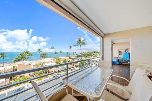 a balcony with a table and chairs and a view of the ocean at Stunning ocean view 2 bedroom Steps from beach in Kihei