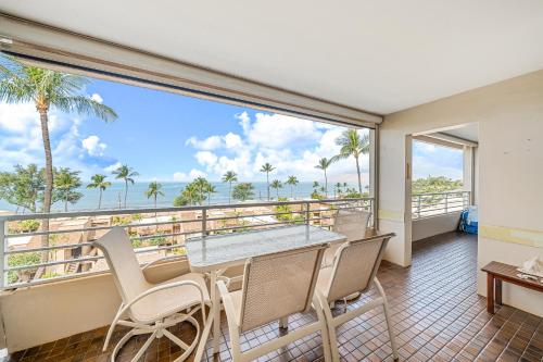a balcony with a table and chairs and a view of the ocean at Stunning ocean view 2 bedroom Steps from beach in Kihei