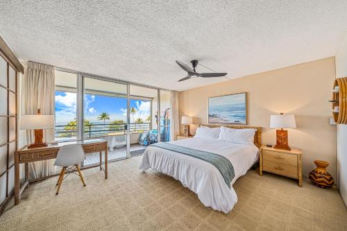 a bedroom with a bed and a desk and windows at Stunning ocean view 2 bedroom Steps from beach in Kihei
