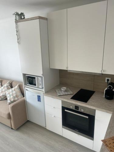 une petite cuisine avec des placards blancs et un canapé dans l'établissement Bright & Spacious Studio near La Croisette, à Cannes