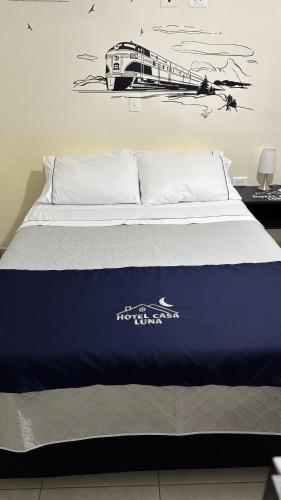 a bed with a blue comforter and a train on the wall at Hotel Casa Luna in Bogotá