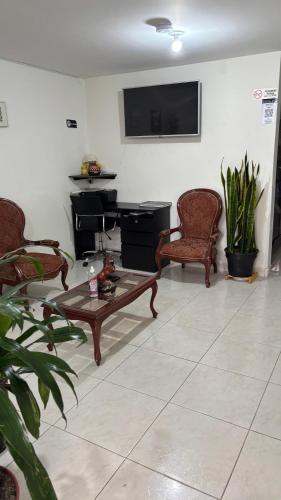a living room with chairs and a table and a tv at Hotel Casa Luna in Bogotá
