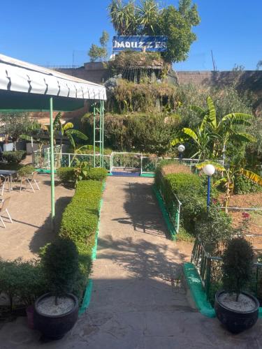 a garden with bushes and a sign in the background at Hôtel Imouzzer in Ourika