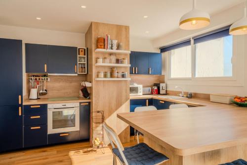 une cuisine avec des placards bleus et une table en bois dans l'établissement Appartement avec terrasse et vue mer, à Cannes