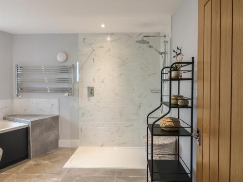 ein Badezimmer mit Dusche und schwarzem Regal in der Unterkunft Barley Cottage in Huntingdon