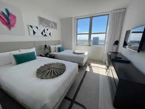 una camera d'albergo con due letti e una televisione di Apt Hyde, Beach, Pool, and Resort Amenities in Miami a Hollywood