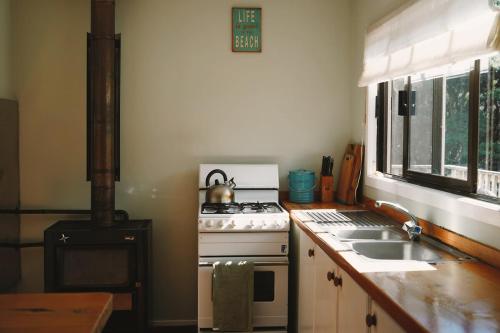 a kitchen with a stove and a sink at Okupu Beach House in Okupu