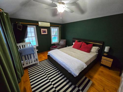 a bedroom with green walls and a bed with red pillows at Oceanfront Dock of the Bay Retreat in Scotts Hill