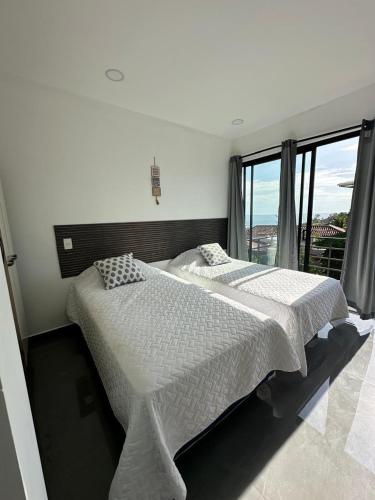 a bedroom with two beds and a large window at St Michaels Ocean View House in El Zonte