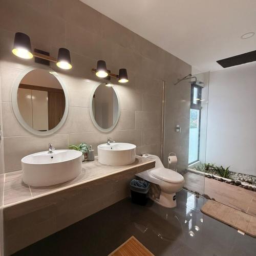 a bathroom with two sinks and a toilet and mirrors at St Michaels Ocean View House in El Zonte