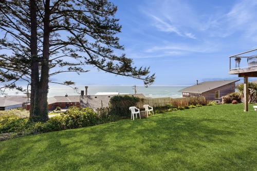 a yard with two white chairs in the grass at Hale Kaalawai Unit B in Oceanside