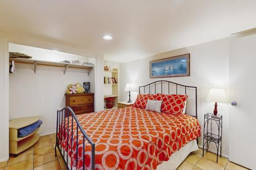 a bedroom with a bed with an orange bedspread at Hale Kaalawai Unit B in Oceanside