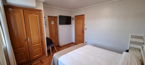 a bedroom with a bed and a chair in it at Hotel Miramar Playa America Nigran in Nigrán