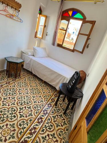 a bedroom with a bed and a table and a window at Dar Yema in Asilah