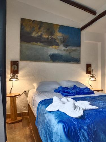 a bedroom with a blue bed with towels on it at Apartaestudios La Baranda in Salento