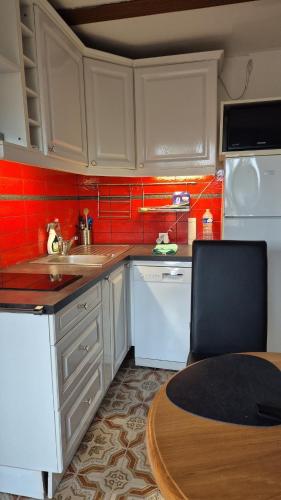 une cuisine avec des placards blancs, une table et du carrelage rouge dans l'établissement Le st françois, à Fréjus