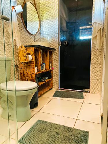 a bathroom with a toilet and a glass door at Hostel Caraivando in Caraíva