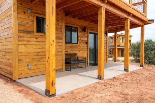a wooden house with a porch with a bench on it at Tiny Cabin #3 at The Cedars in Kanab