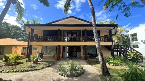 a house with a balcony and palm trees at Rainbow&Resort in Nadi