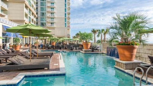 une piscine avec chaises et parasols dans un hôtel dans l'établissement Hilton Vacation Club Ocean Beach Club, à Virginia Beach