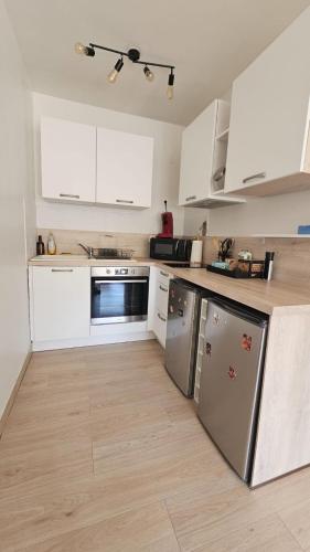 une cuisine avec des armoires blanches et des appareils en acier inoxydable dans l'établissement Hyper Centre Apartment with Garage, au Mans