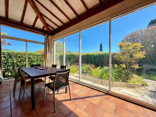 - une salle à manger avec une table, des chaises et de grandes fenêtres dans l'établissement Maison provençale - Plage 500m, à Carqueiranne