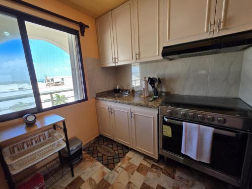 a kitchen with a stove and a large window at Ocean view condo with balcony hotel zone Cancun in Cancún