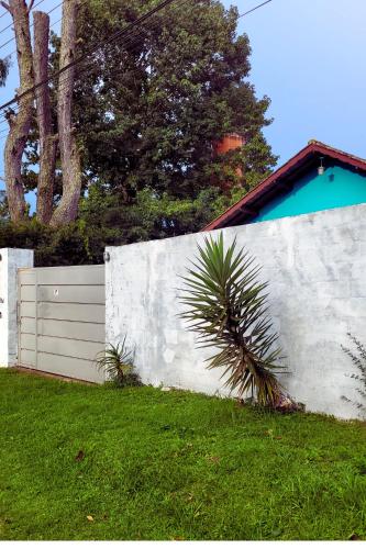 a white fence with a palm tree in a yard at Cantinho Dona Cleide in Monte Verde